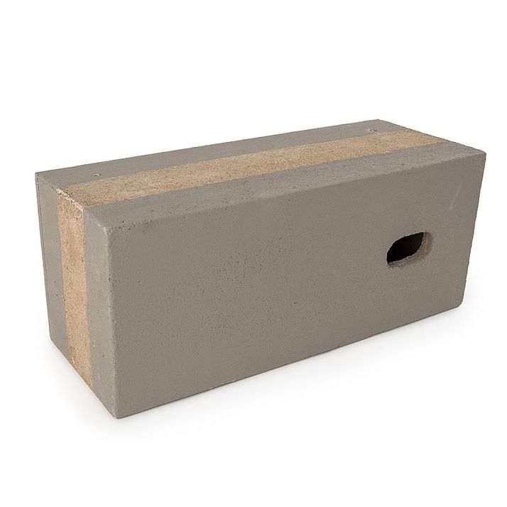 A rectangular gray concrete block with light brown stripes along its top and one end, and a rectangular hole on a side.