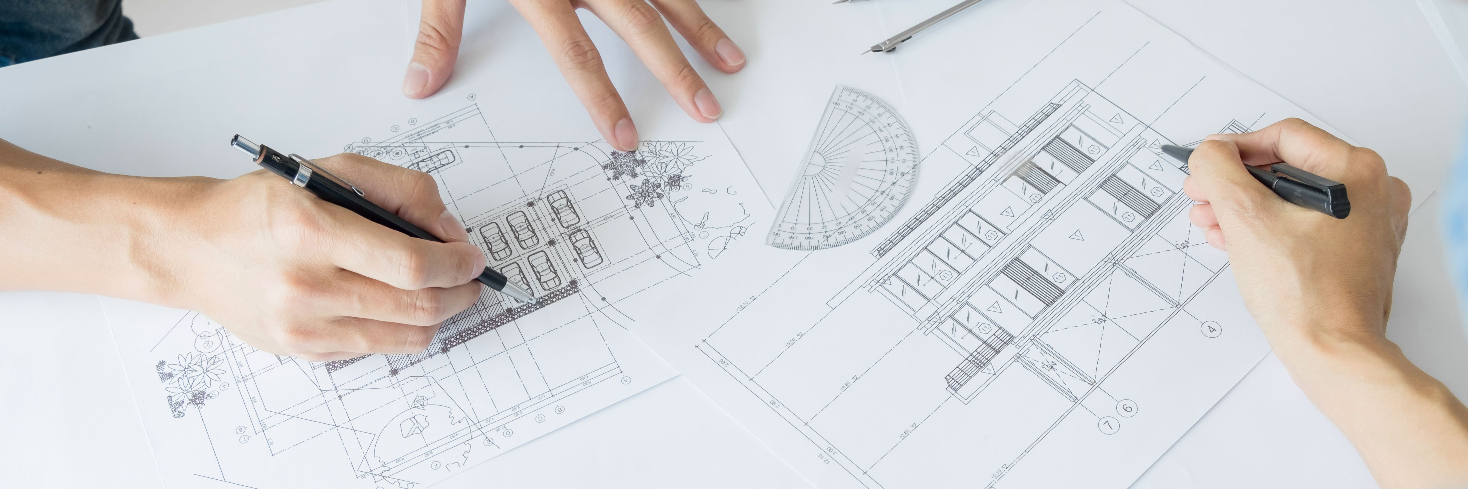2 handen met pennen die aan het tekenen zijn op bouwtekeningen