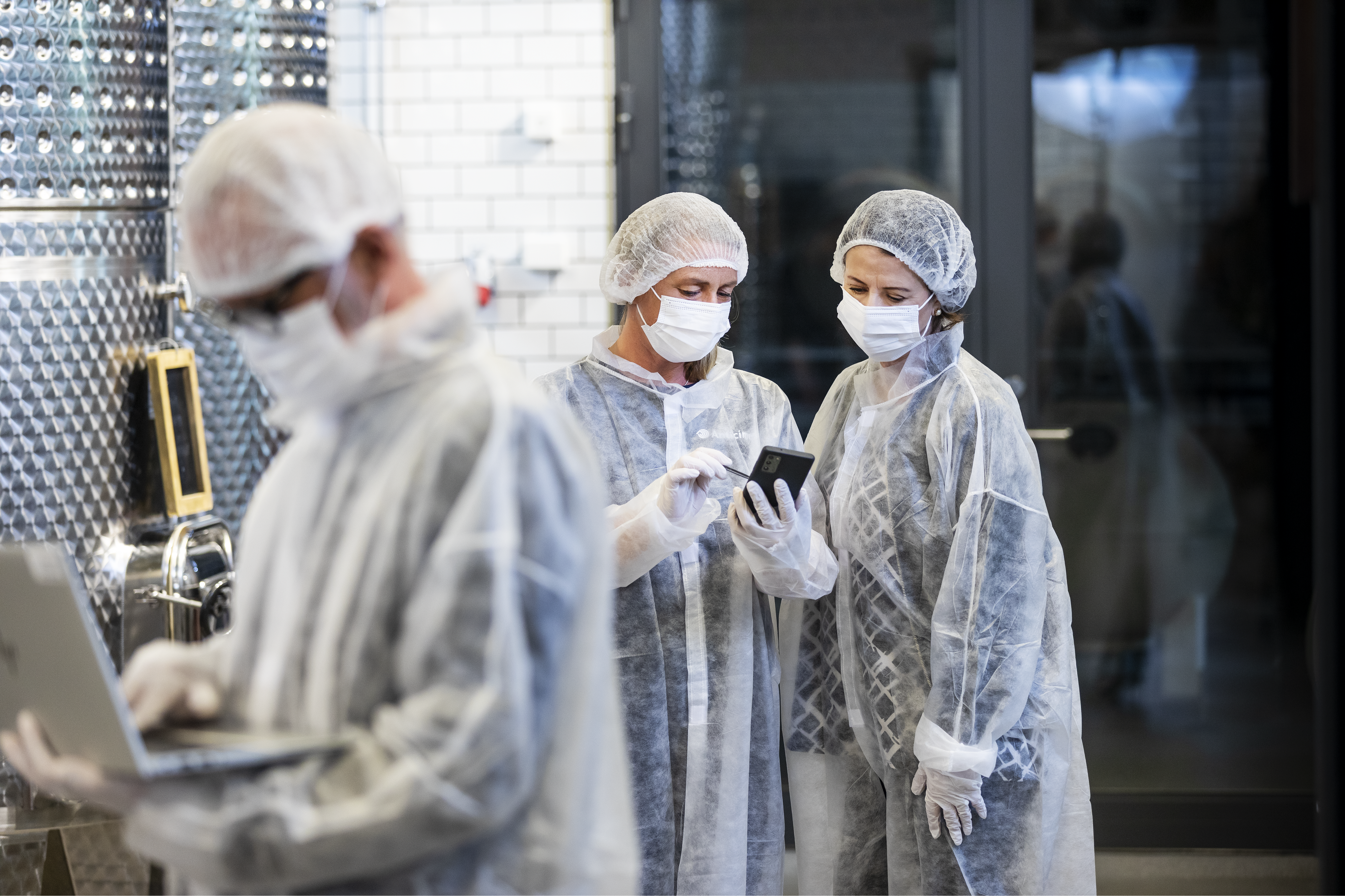 Tre anställda inom livsmedelshantering utför egenkontrollsprogram i dator och mobil