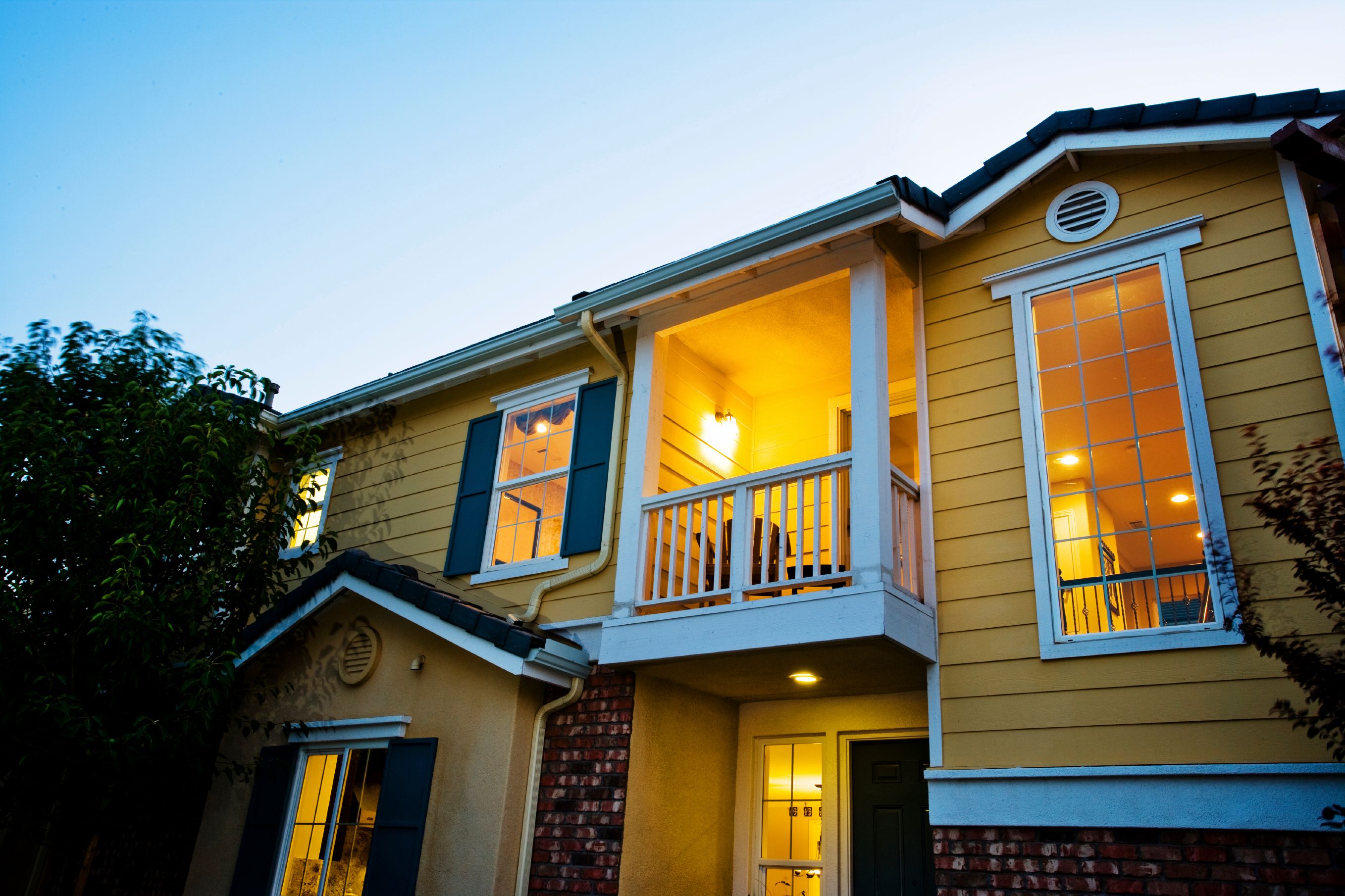 Gul trävilla med vita detaljer och tänd belysning efter energideklaration