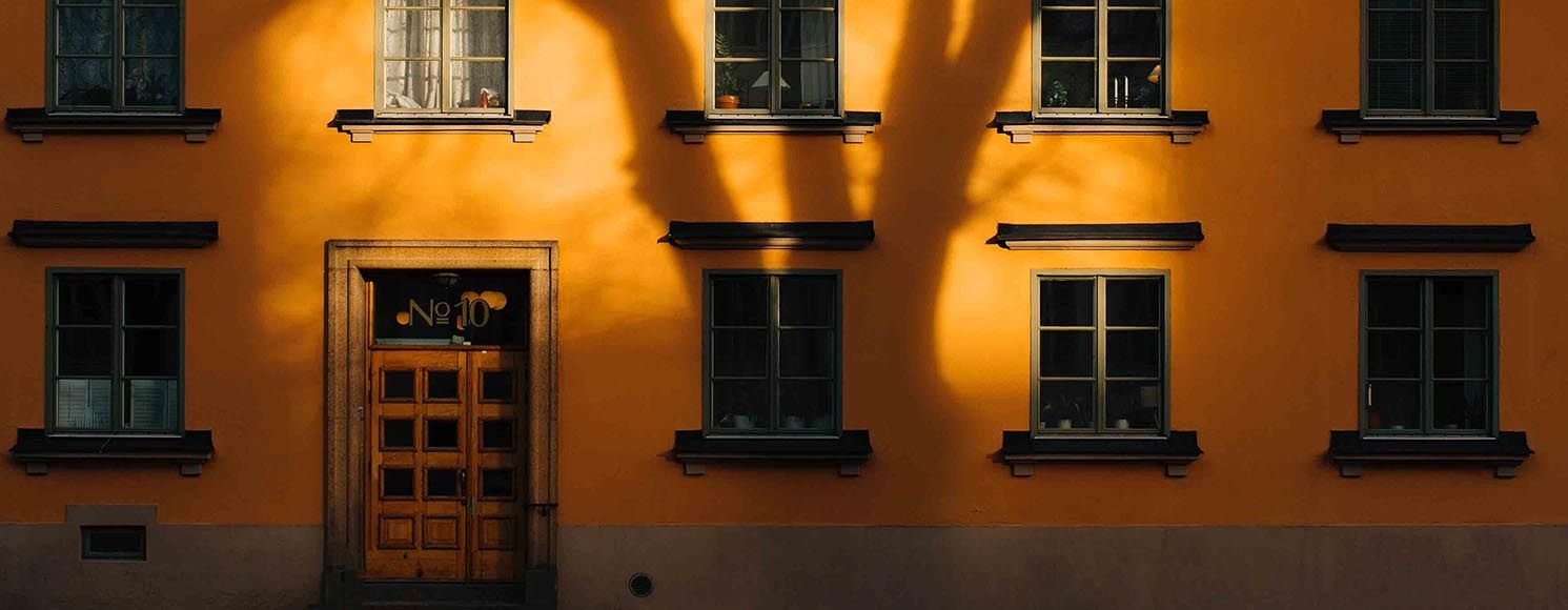 Gult flerbostadshus med fasad i solljus