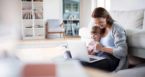 Kvinna som sitter med ett barn och en dator på ett golv i ett hem utan fara för radon