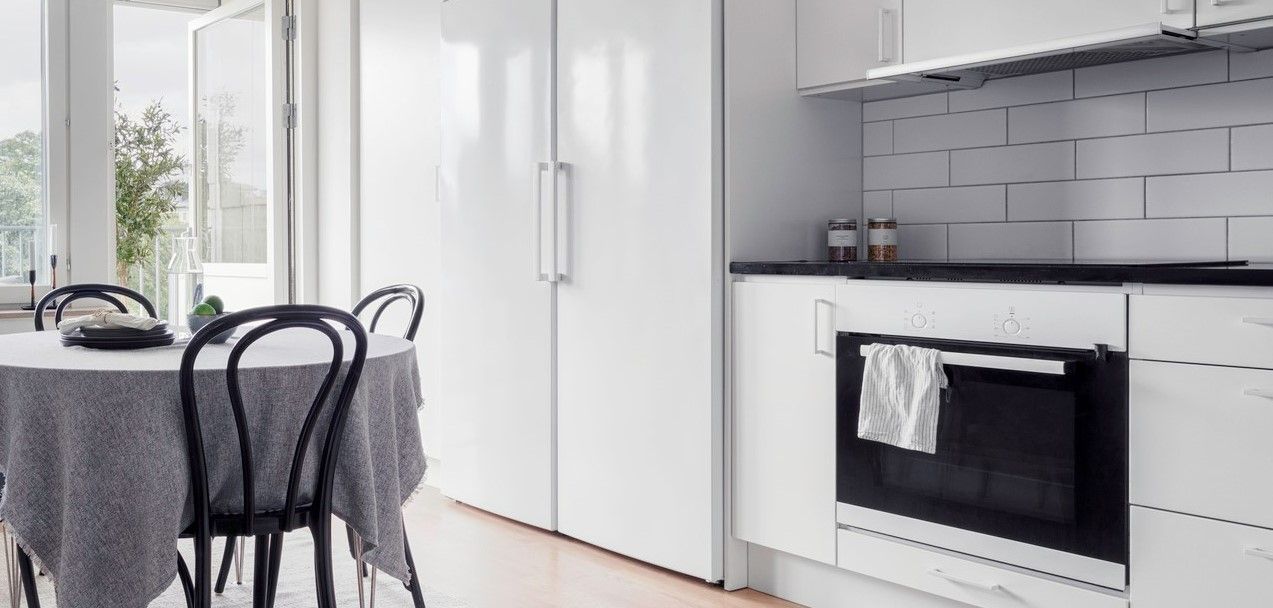 Vitt kök med matbord och öppen balkongdörr