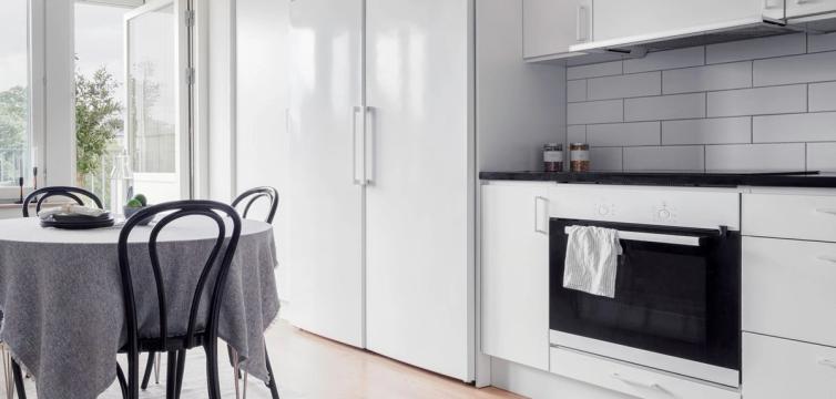 Vitt kök med matbord och öppen balkongdörr