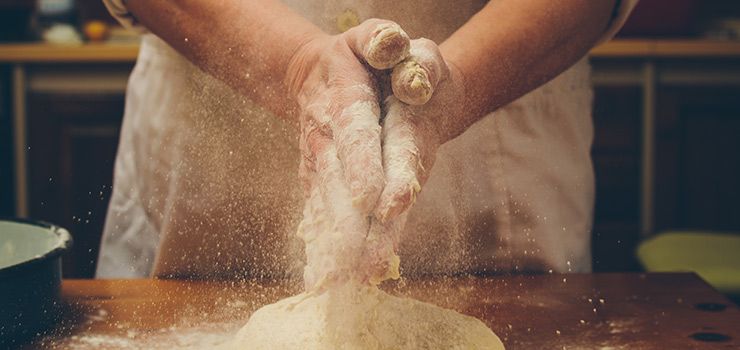 Bagare med mjöliga händer över deg