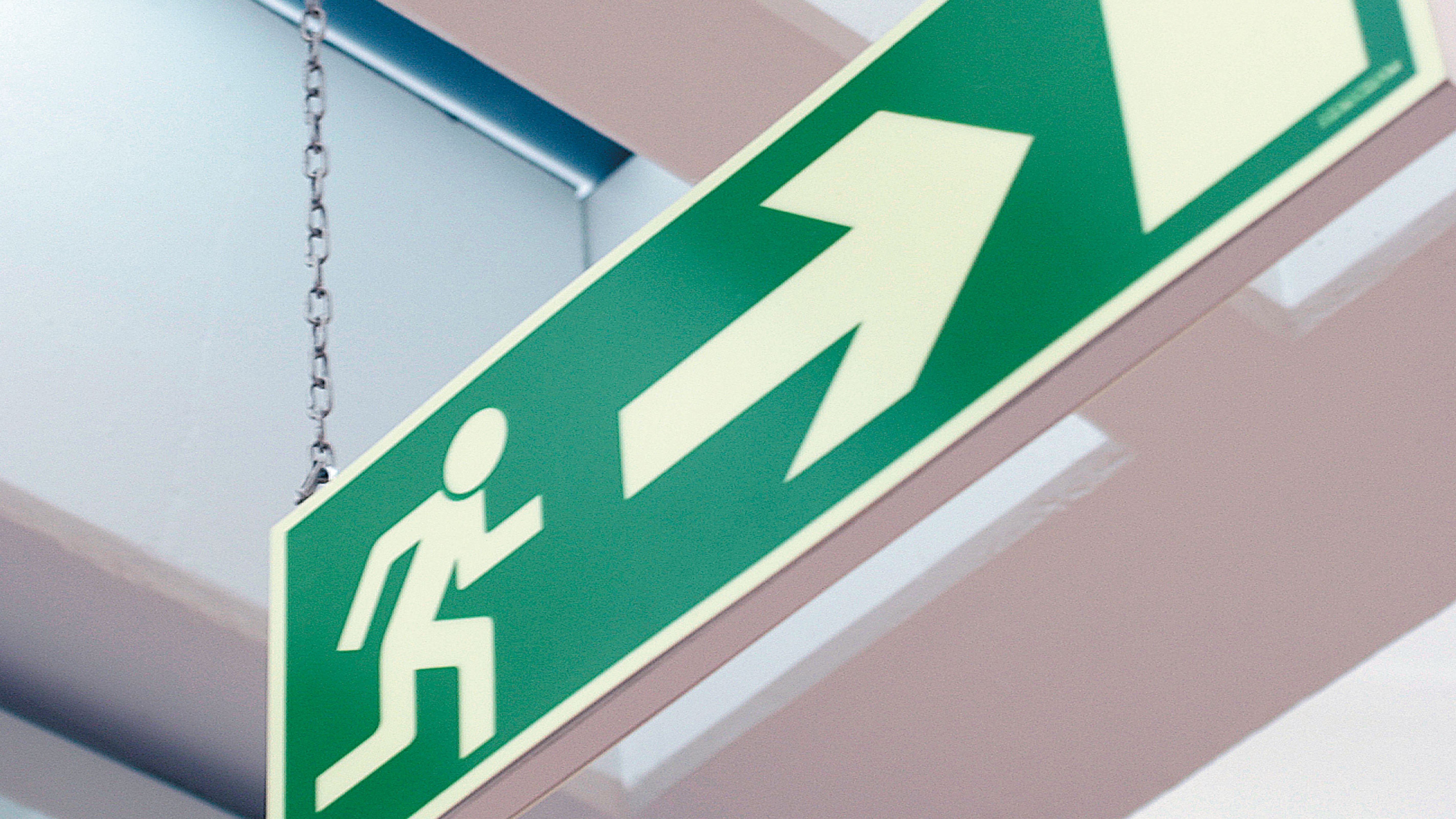 Grön utrymningsvägs-skylt ovanför en entré