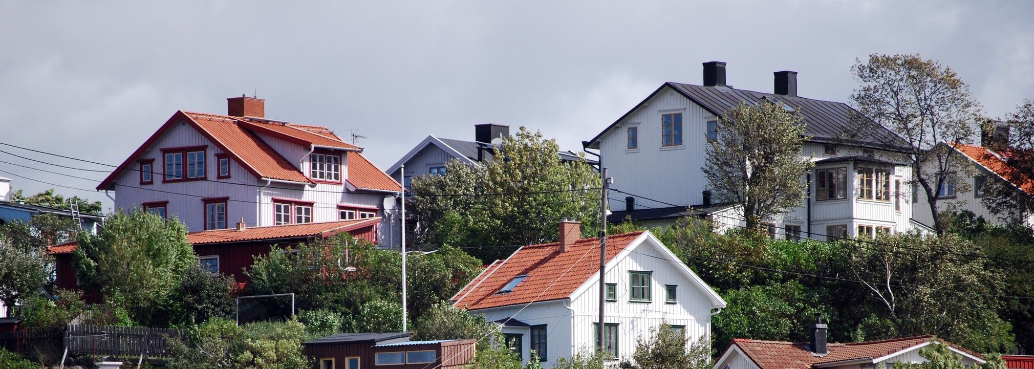 Vy över trävillor på en kulle omgivna av träd och växtlighet