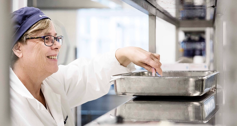Anticimex matsäkerhetstekniker gör mätningar i en metallbehållare i ett industrikök