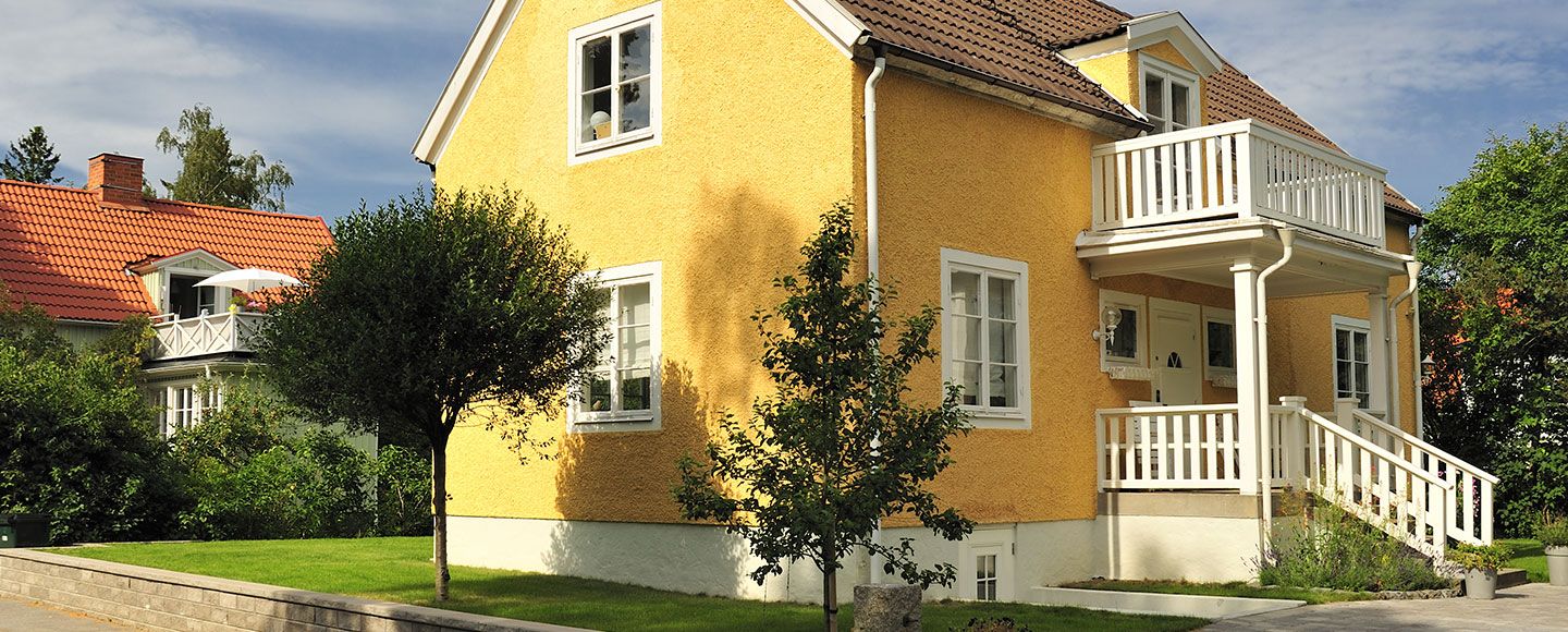 Gult hus med putsad fasad och vita fönster