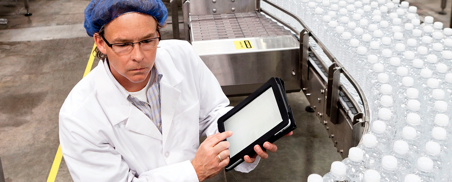 En person inspekterar förpackade flaskor i fabrik för att ge livsmedelskonsultation