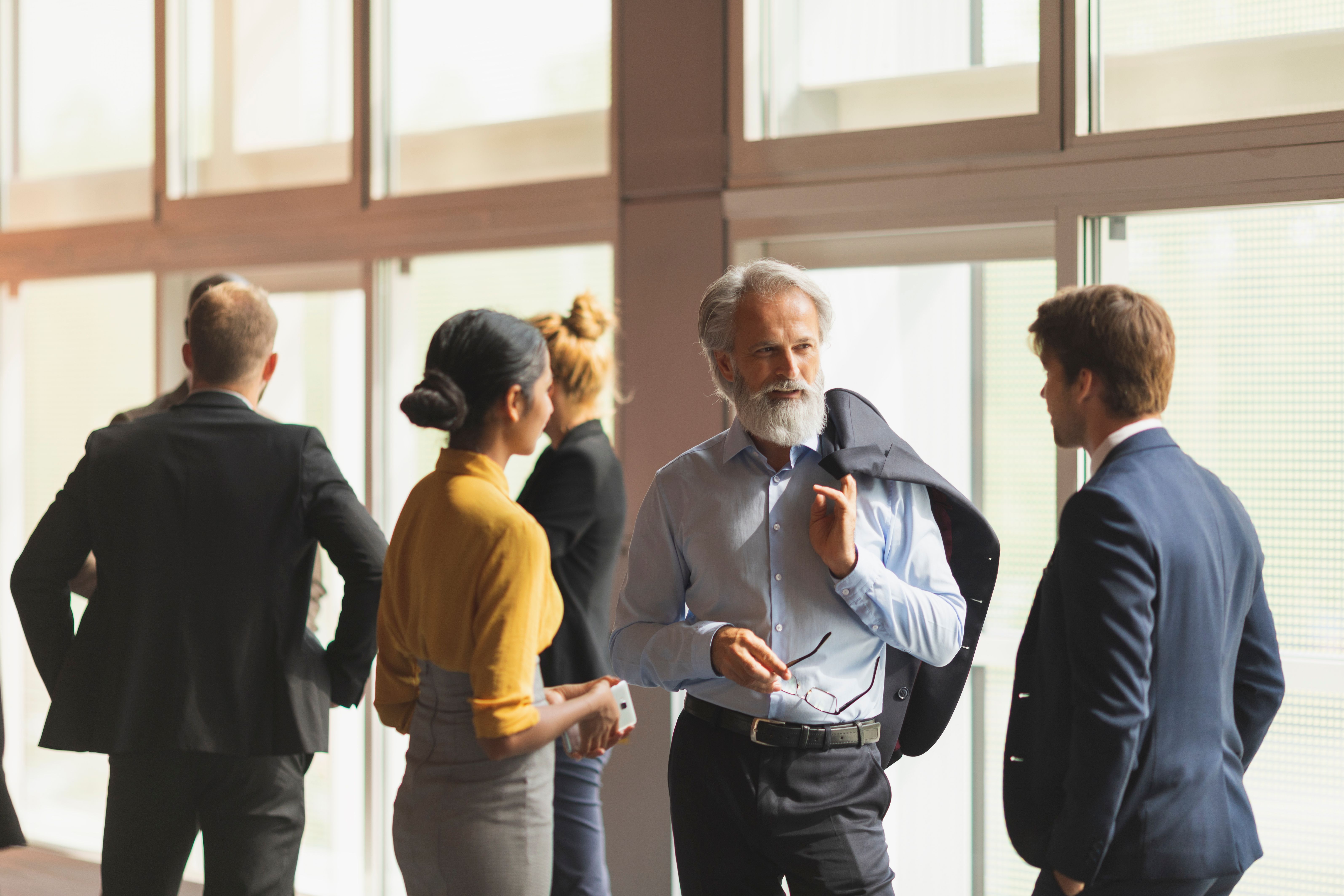 Grupp av försäkringsmäklare i samtal framför fönster