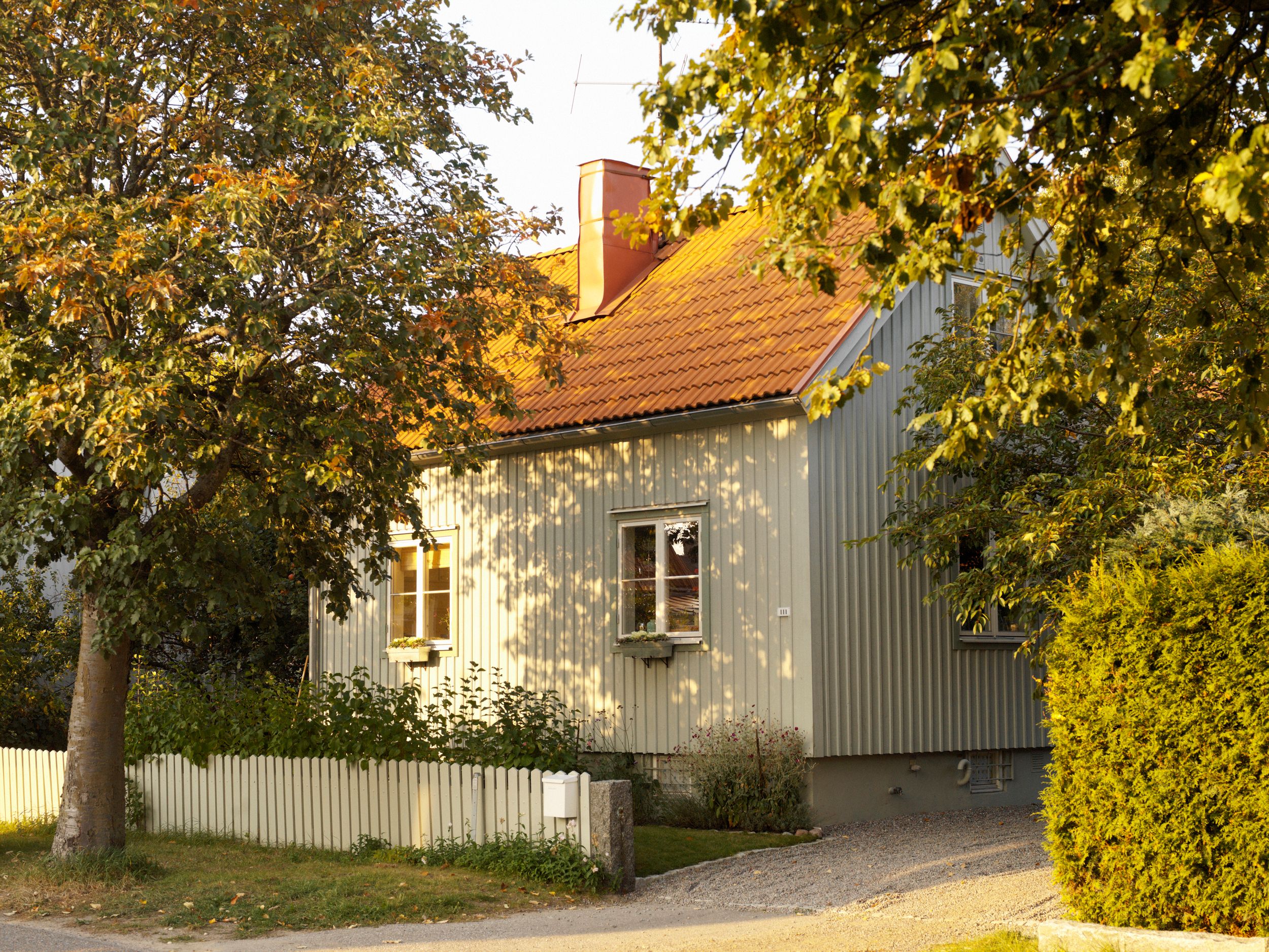 Anticimex Hushälsa - ett vitt hus orange tak och vitt staket i grön trädgård