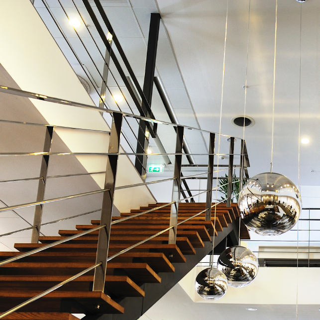 Trappa i trä och metall leder upp till vitmålat tak med röklucka