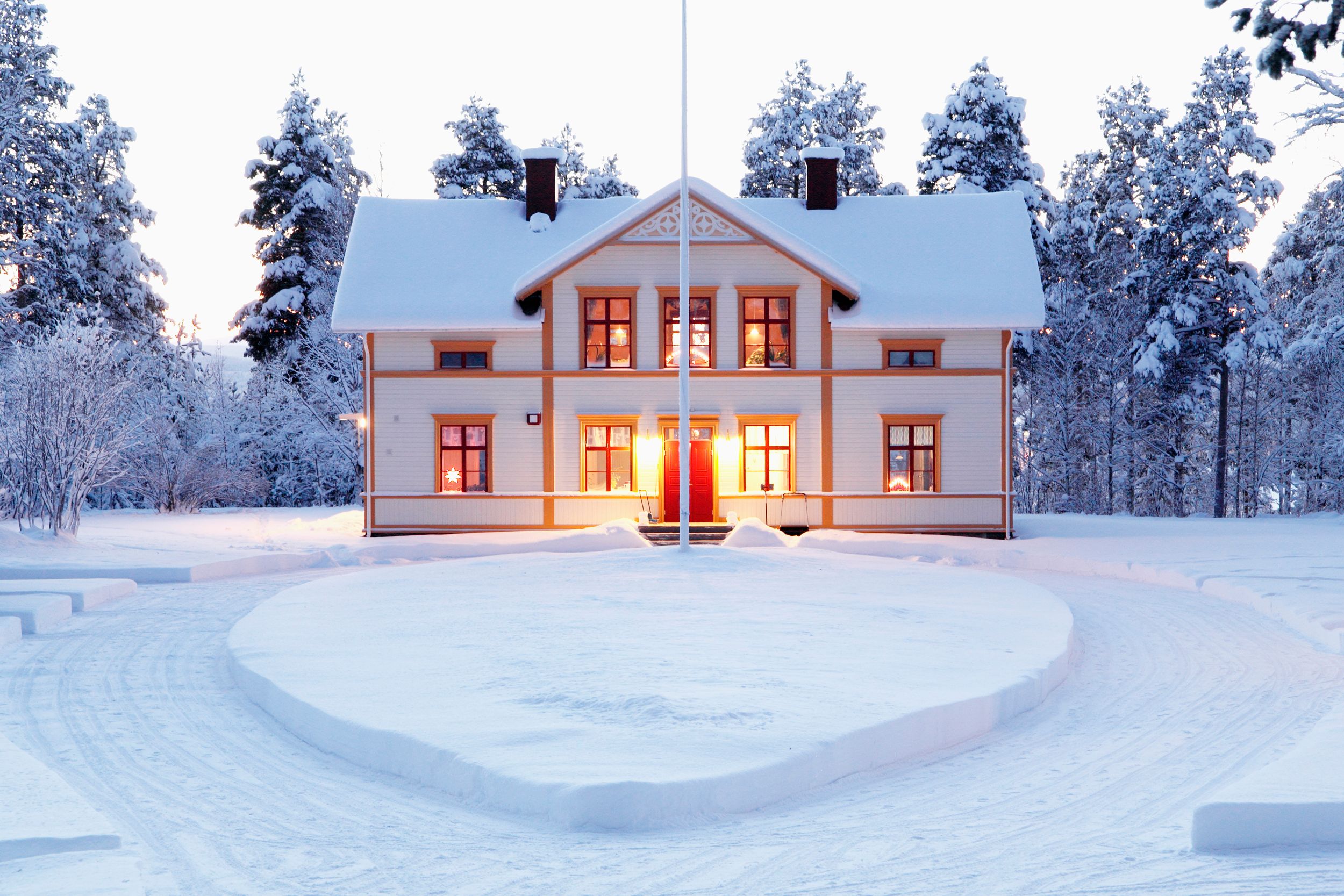 Rött trähus med vita knutar med gula höstlöv i förgrund