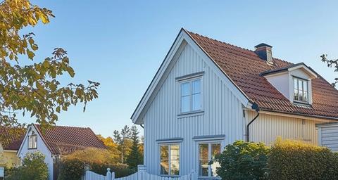 Fasad på vitt trähus i ett soligt villakvarter