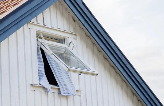Schematisk genomskärning av ett flervåningshus med möblerade rum, garage och källare.