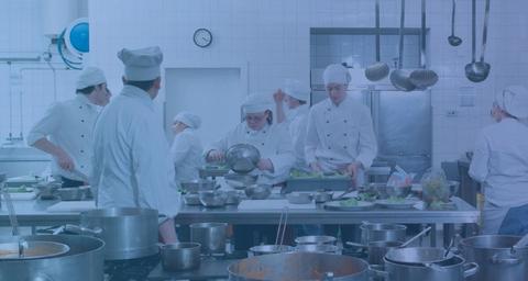 En grupp vitklädda kockar i ett restaurangkök med grytor och kastruller