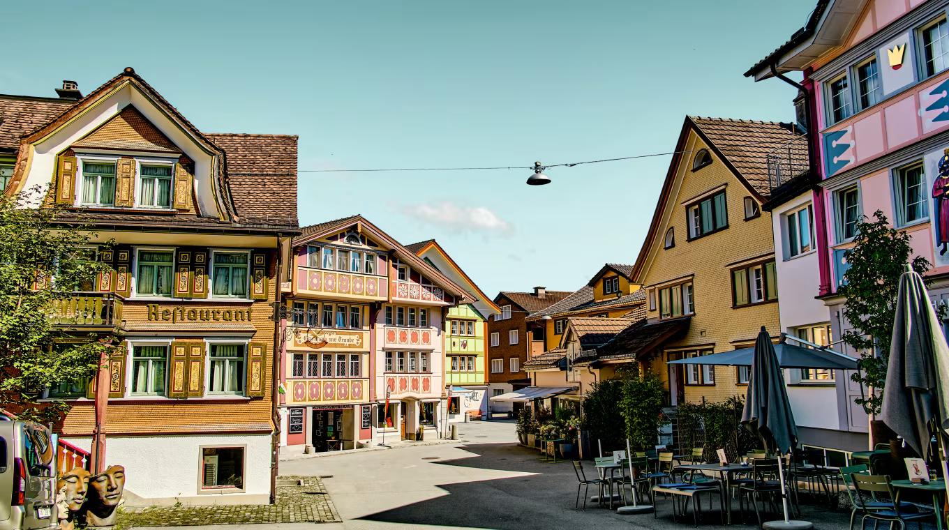 A colorful street lined with traditional buildings with painted facades and outdoor restaurant seating.