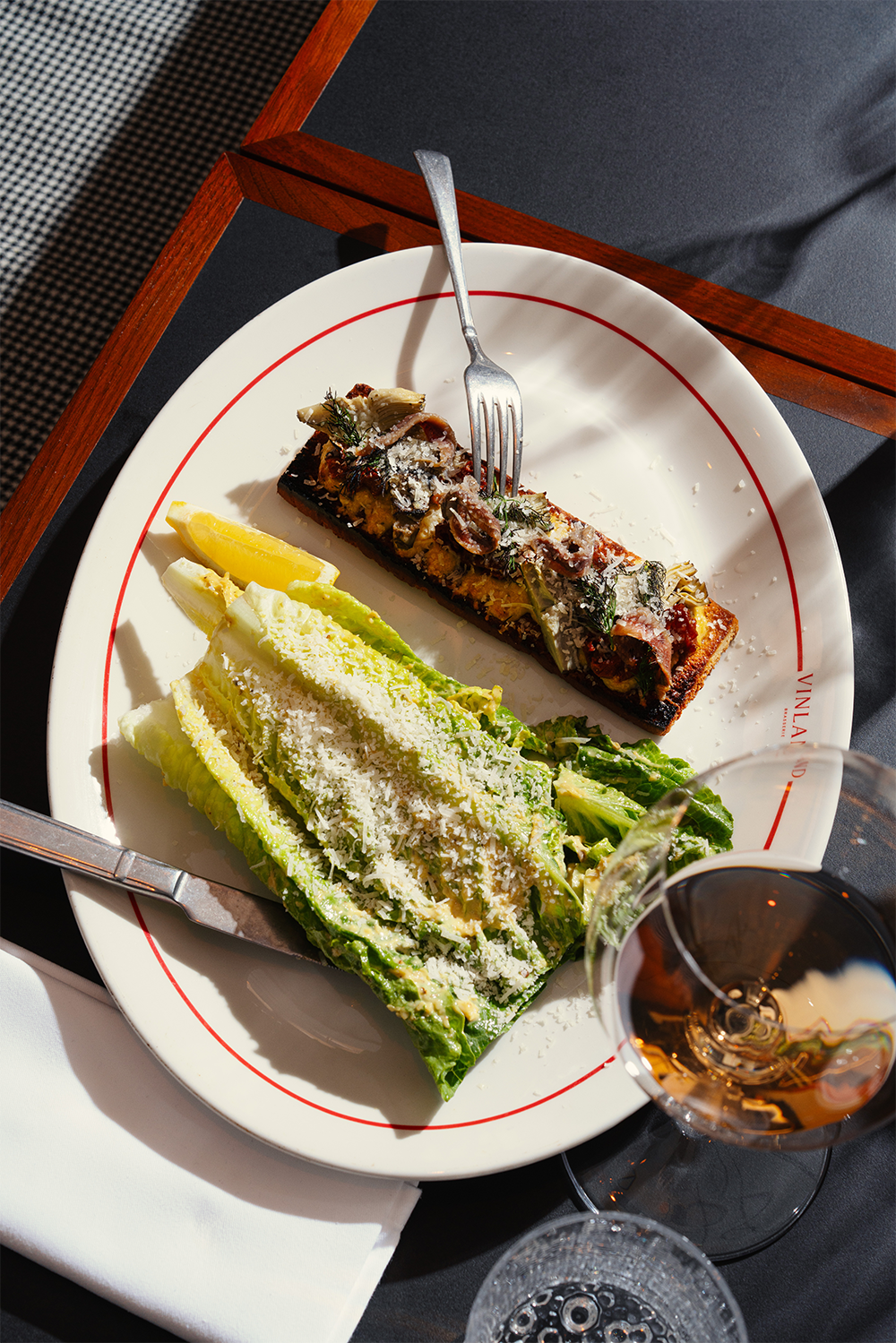 En tallerken med en hovedrett fra Vinland og et glass vin