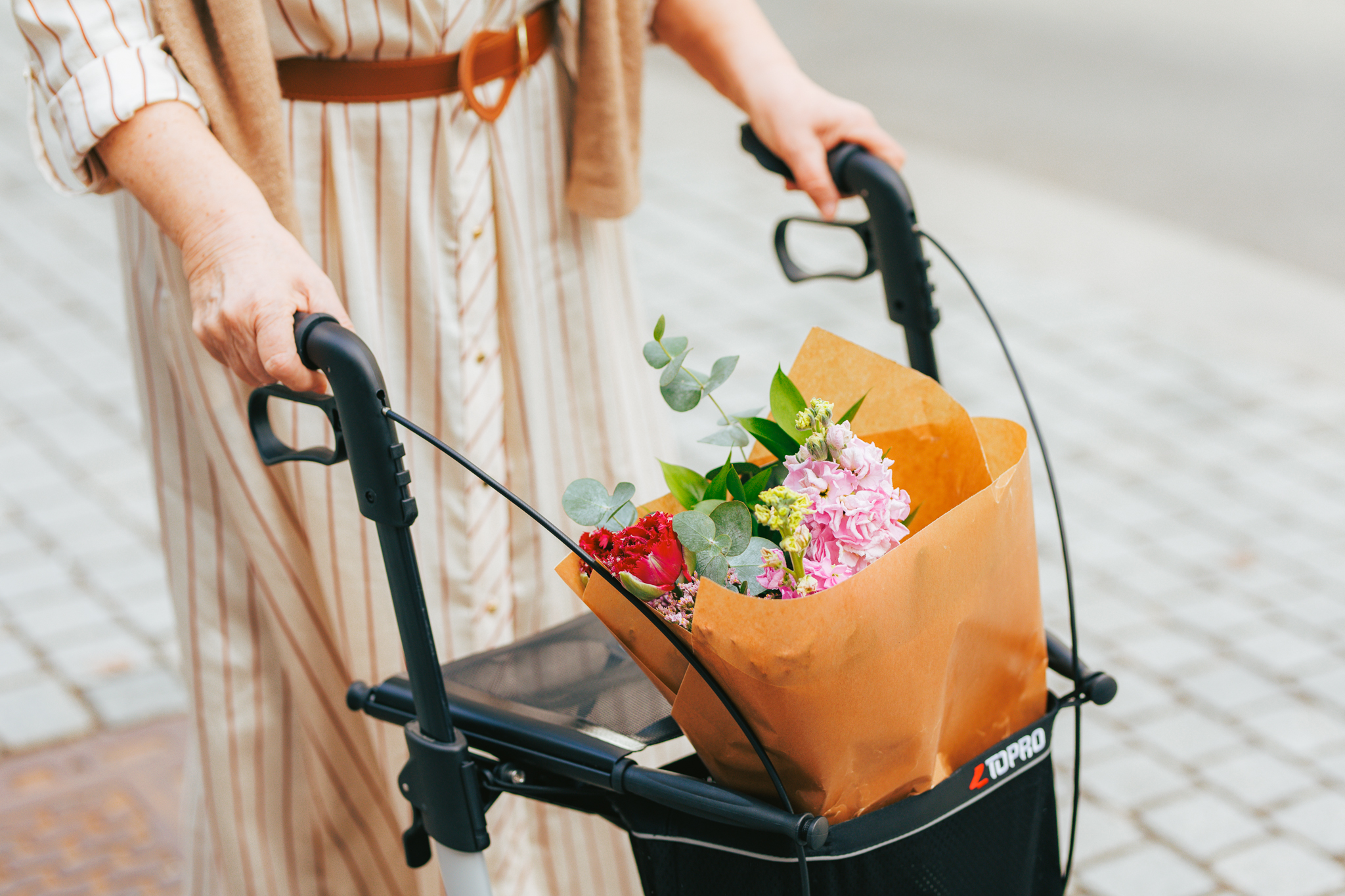Nærbilde av en rullator med en blomsterbukett i kurven