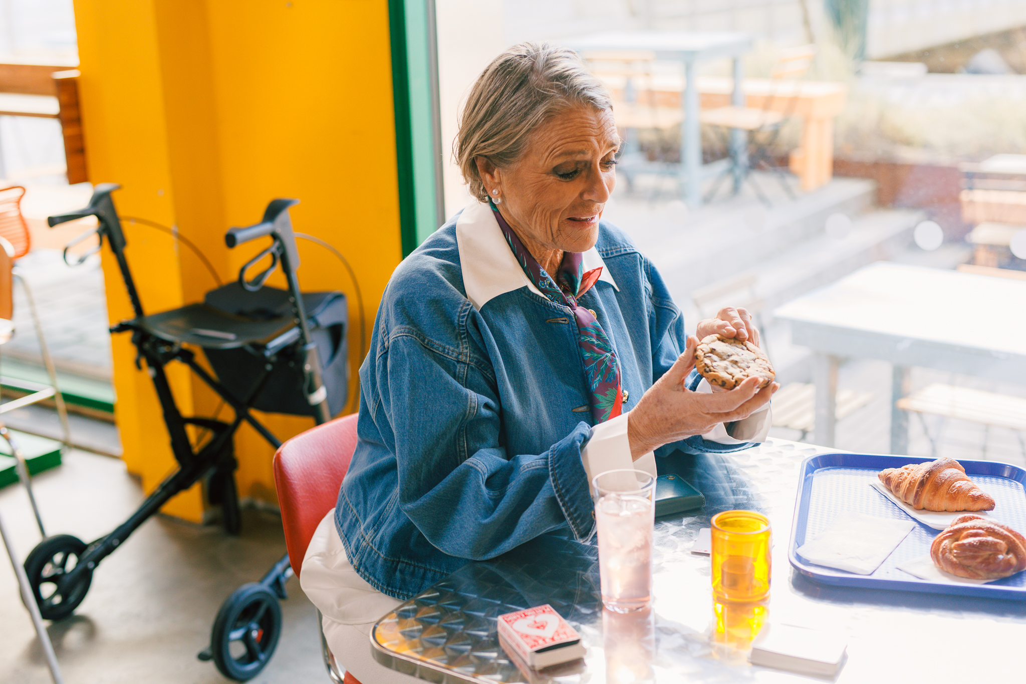 En eldre kvinne spiser bakverk på en kafé. Rullatoren står ved siden av bordet. 