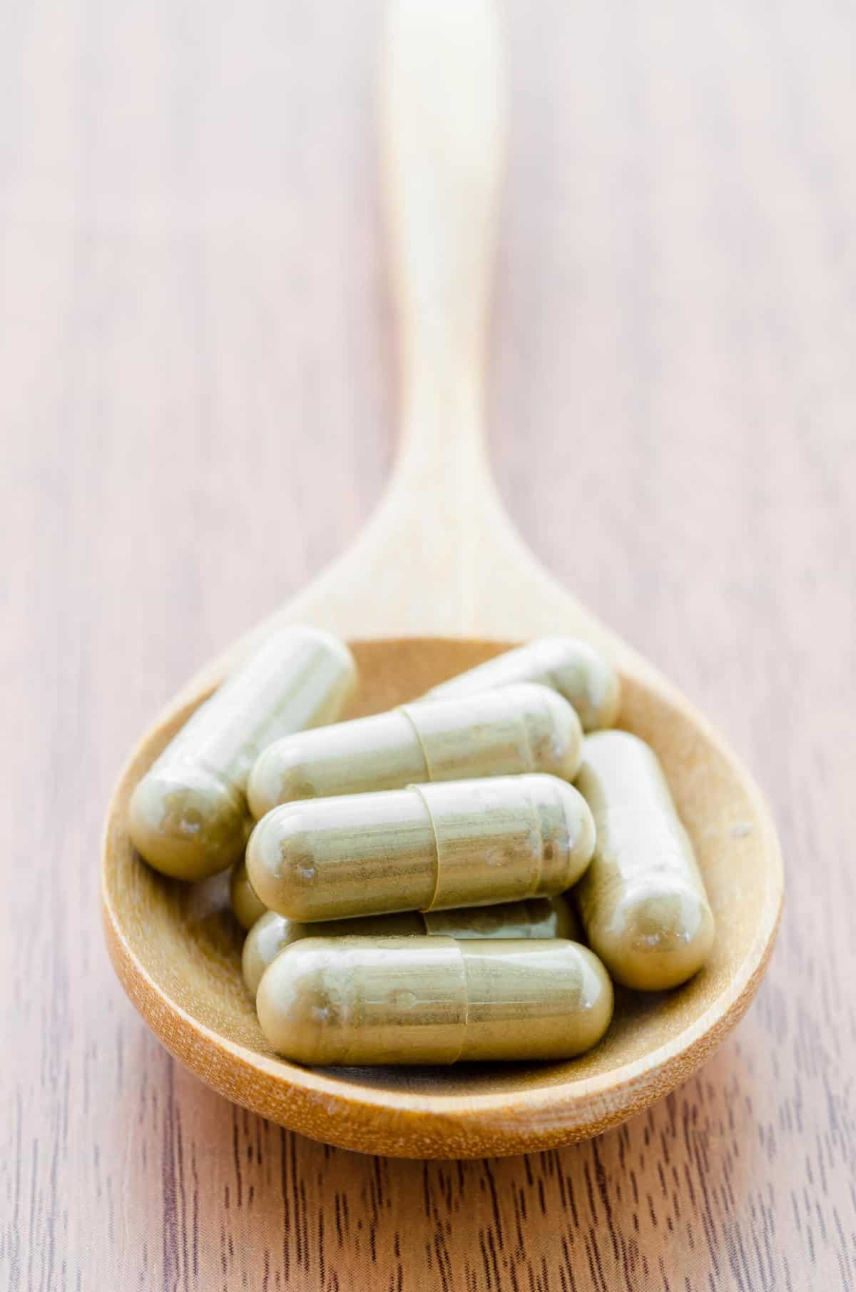 Supplement capsules on wooden spoon