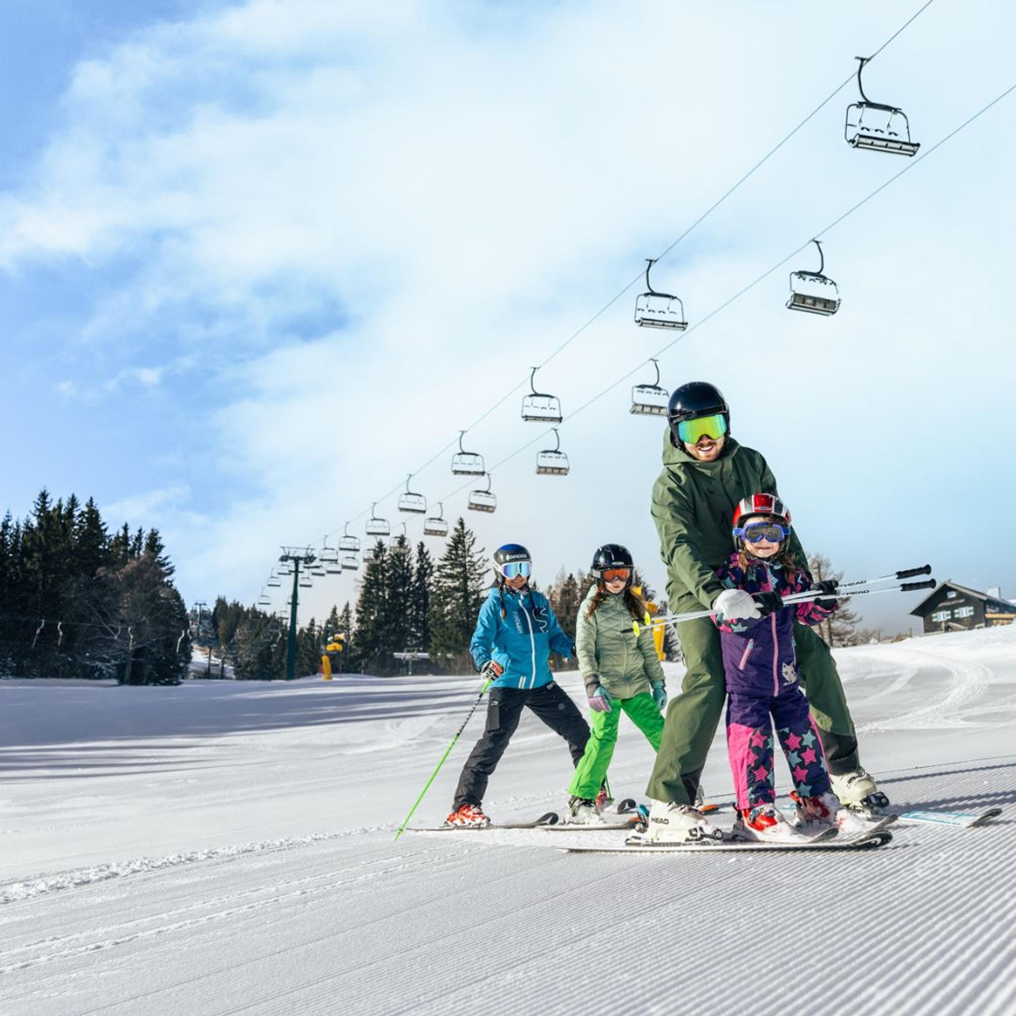 Eine Familie fährt auf Ski gemeinsam die Piste hinunter.