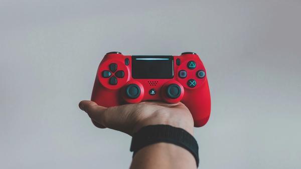 Person holding red playstation controller
