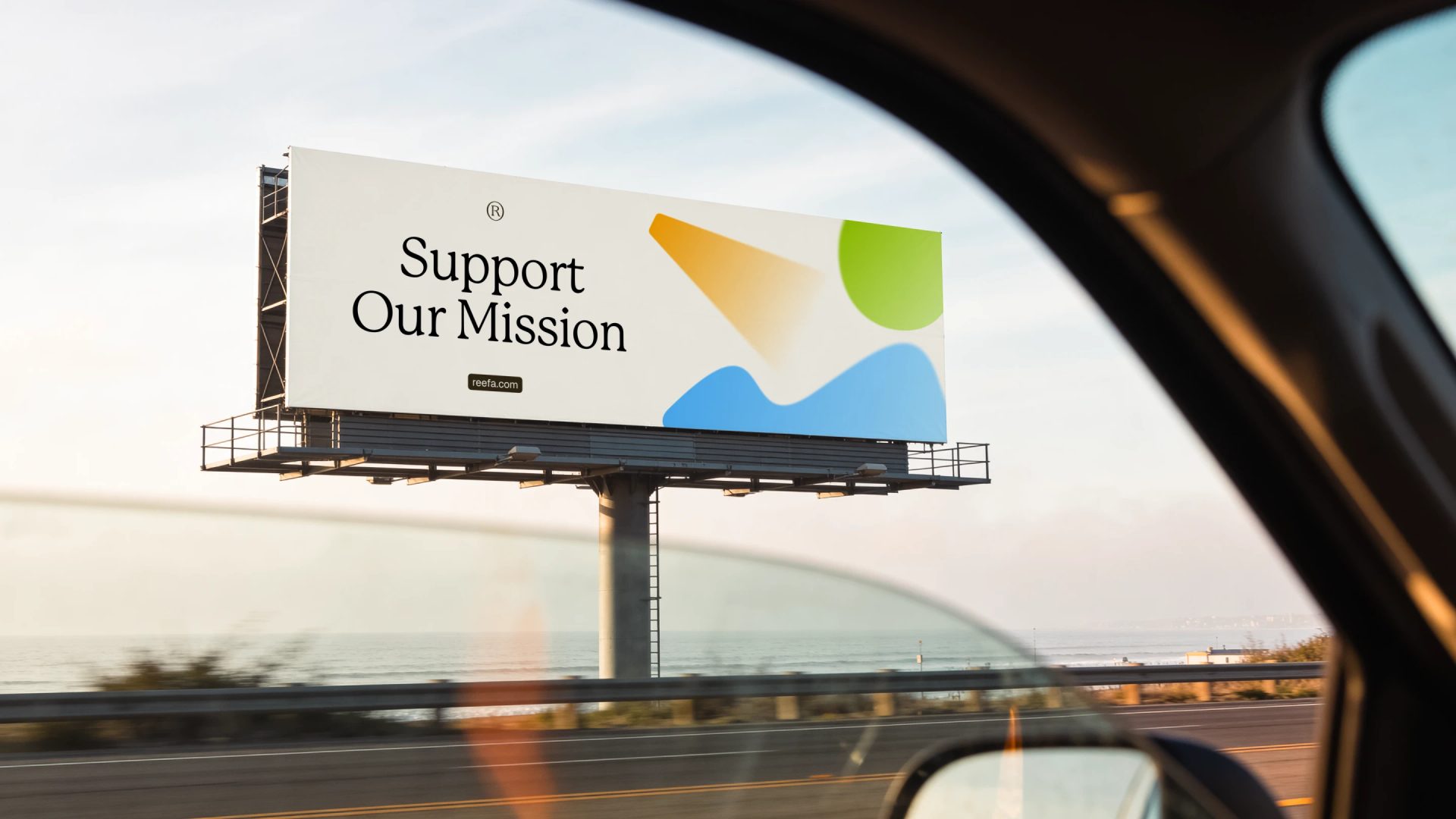 Roadside billboard viewed from a car reads “Support Our Mission” and “reefa.com,” with green, orange and blue shapes.