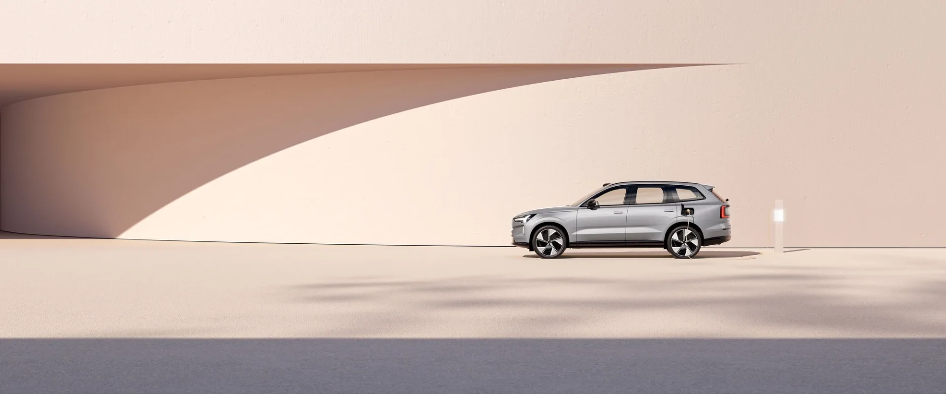 A Volvo EX90 parked in a pale minimal architectural setting