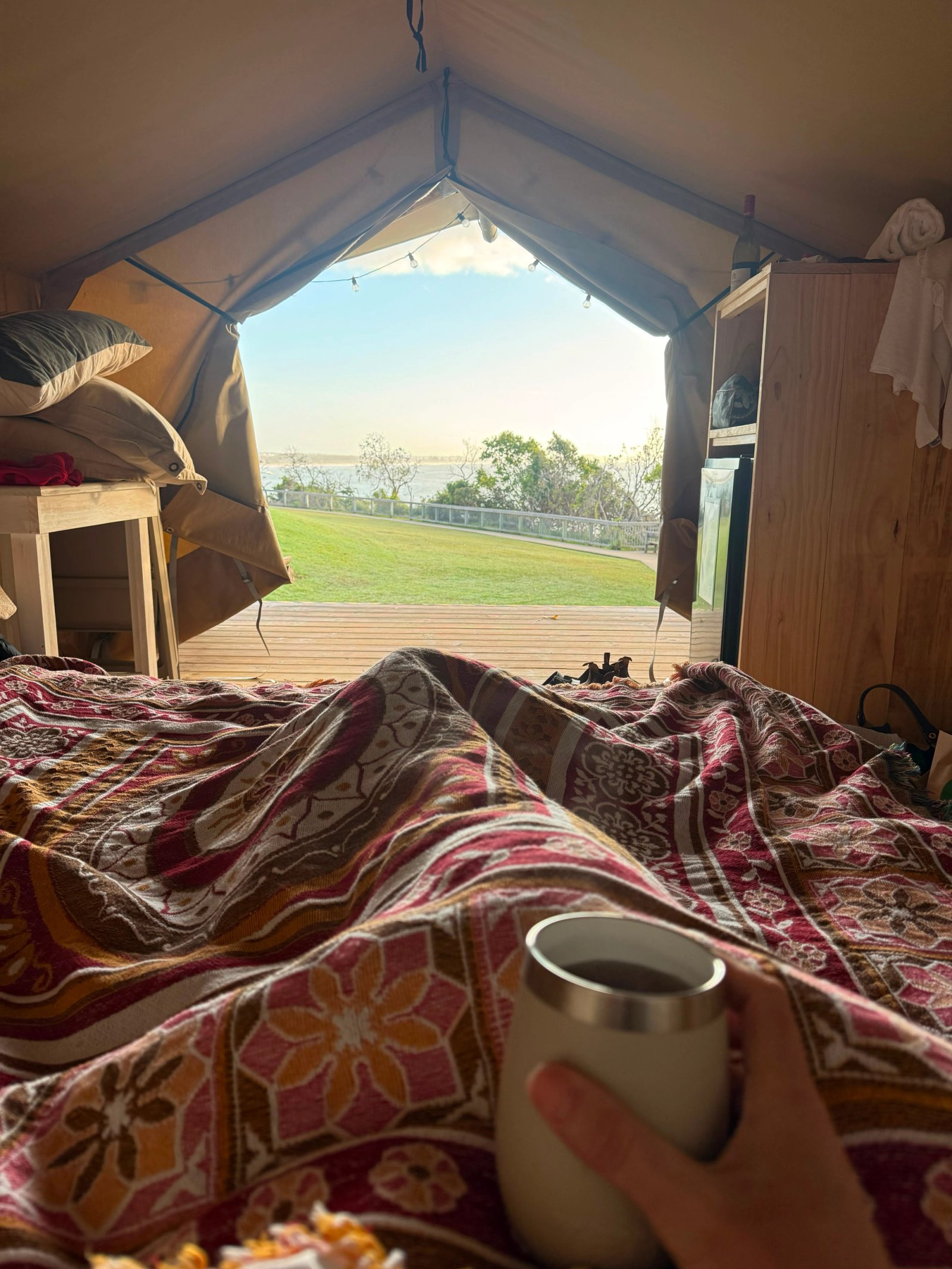 Having a cup of coffee in bed in a glamping tent at Bonny Hills Reflections