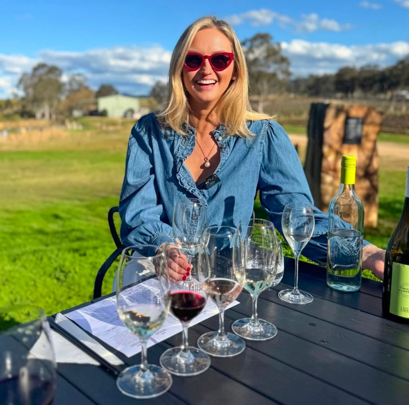 Jen smiling at a wine tasting in the Hunter Valley, with several wine glasses on the table.