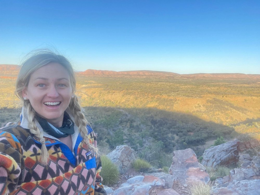 Jen on the Larapinta Trail with red ridgelines stretching across the West MacDonnell Ranges