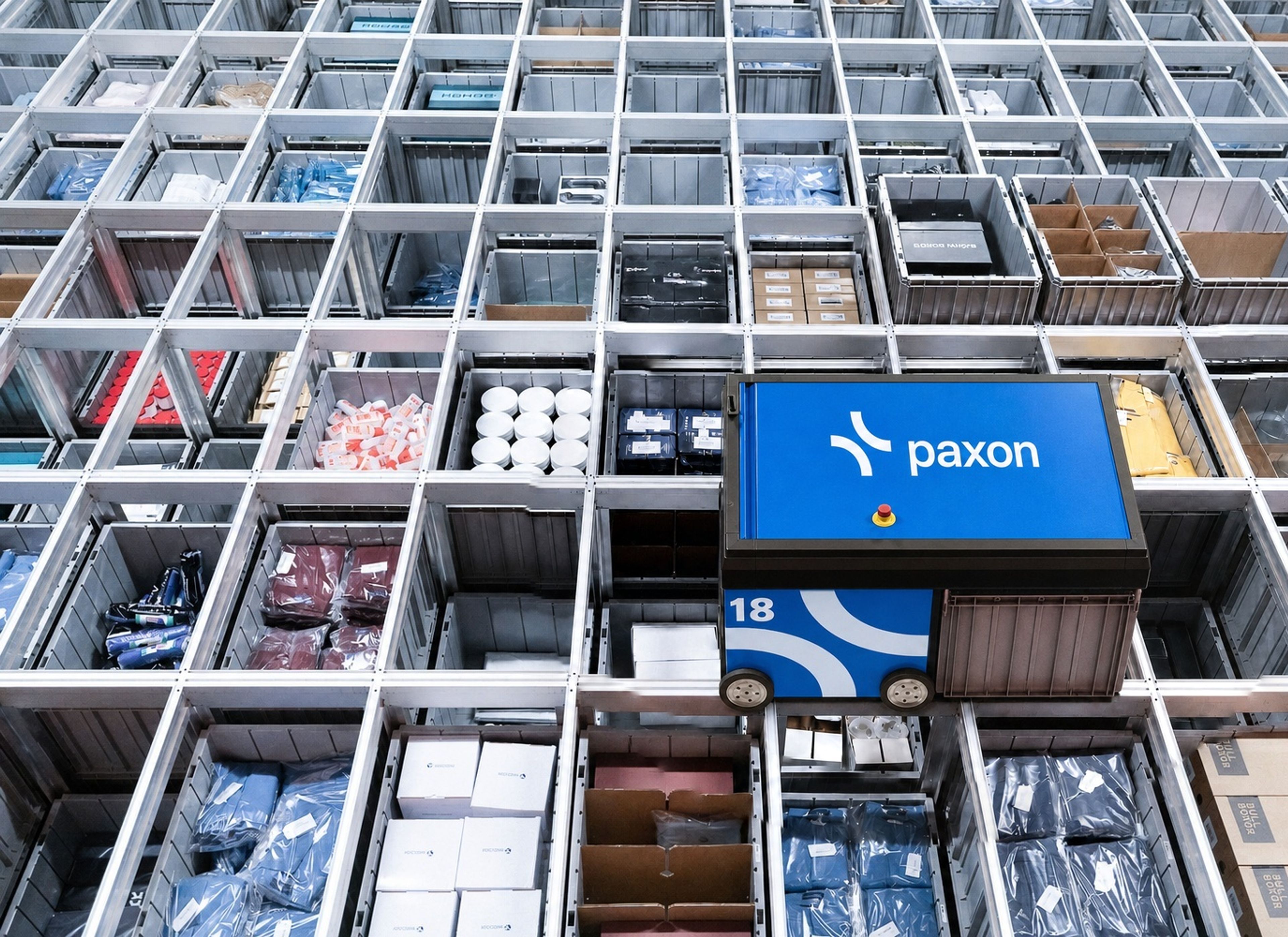 Un robot Paxon se déplace dans un système automatisé de stockage et de récupération sur grille, rempli de bacs de produits.