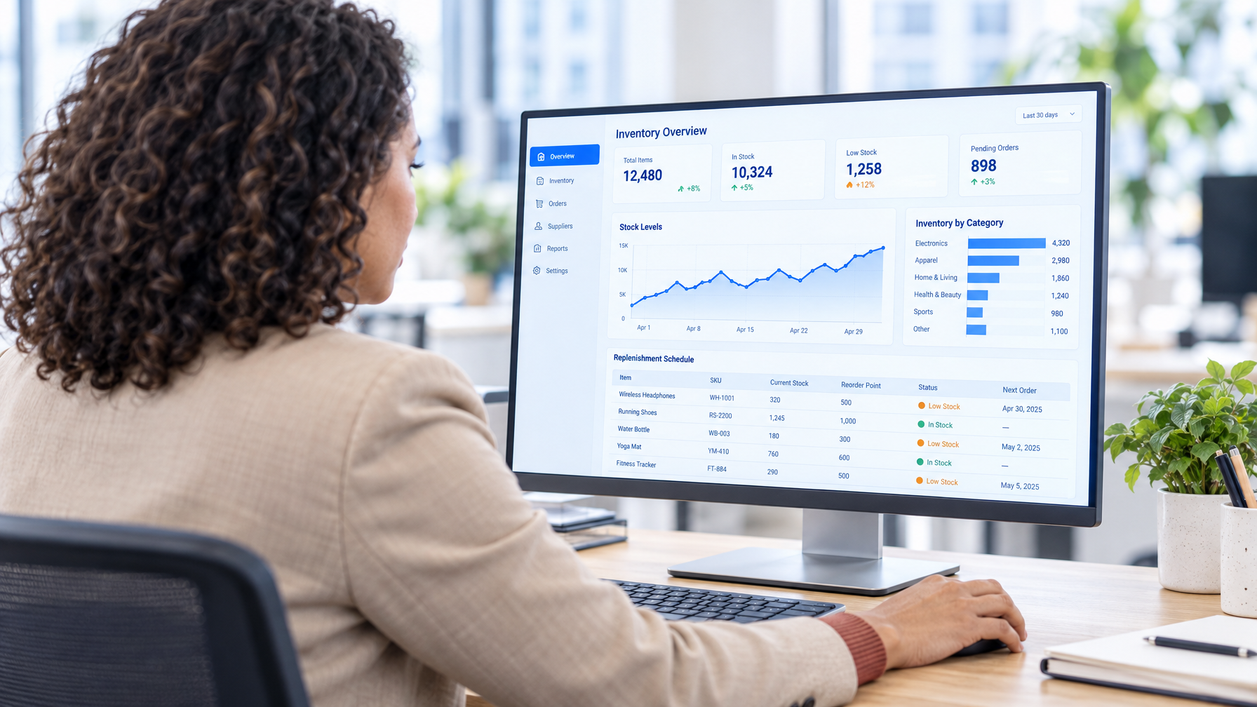 A woman reviews an inventory management dashboard on a desktop computer.