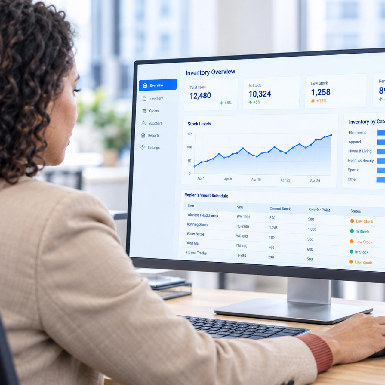 A woman reviews an inventory management dashboard on a desktop computer.