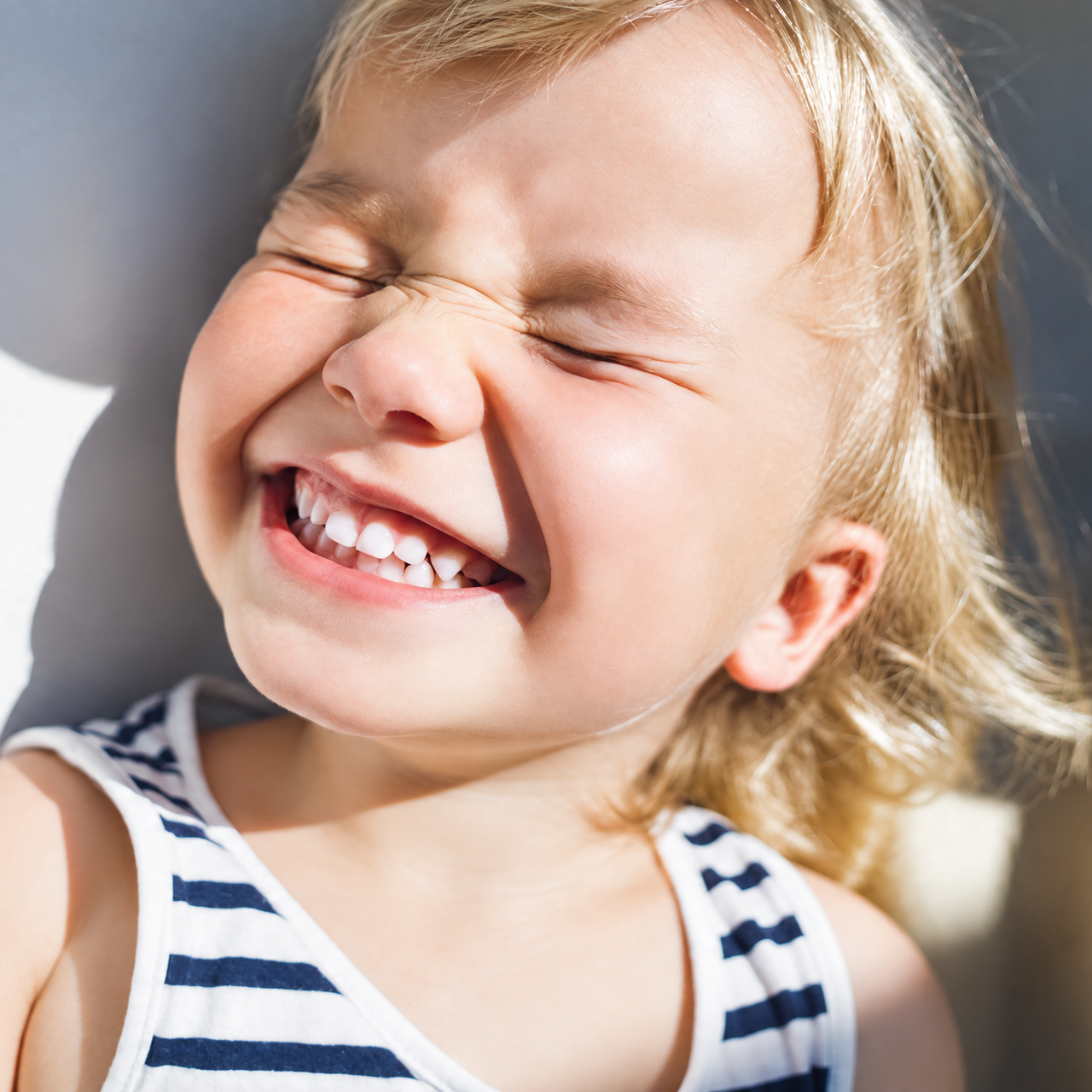 A woman opening a box of baby items in a nursery, reading a card.