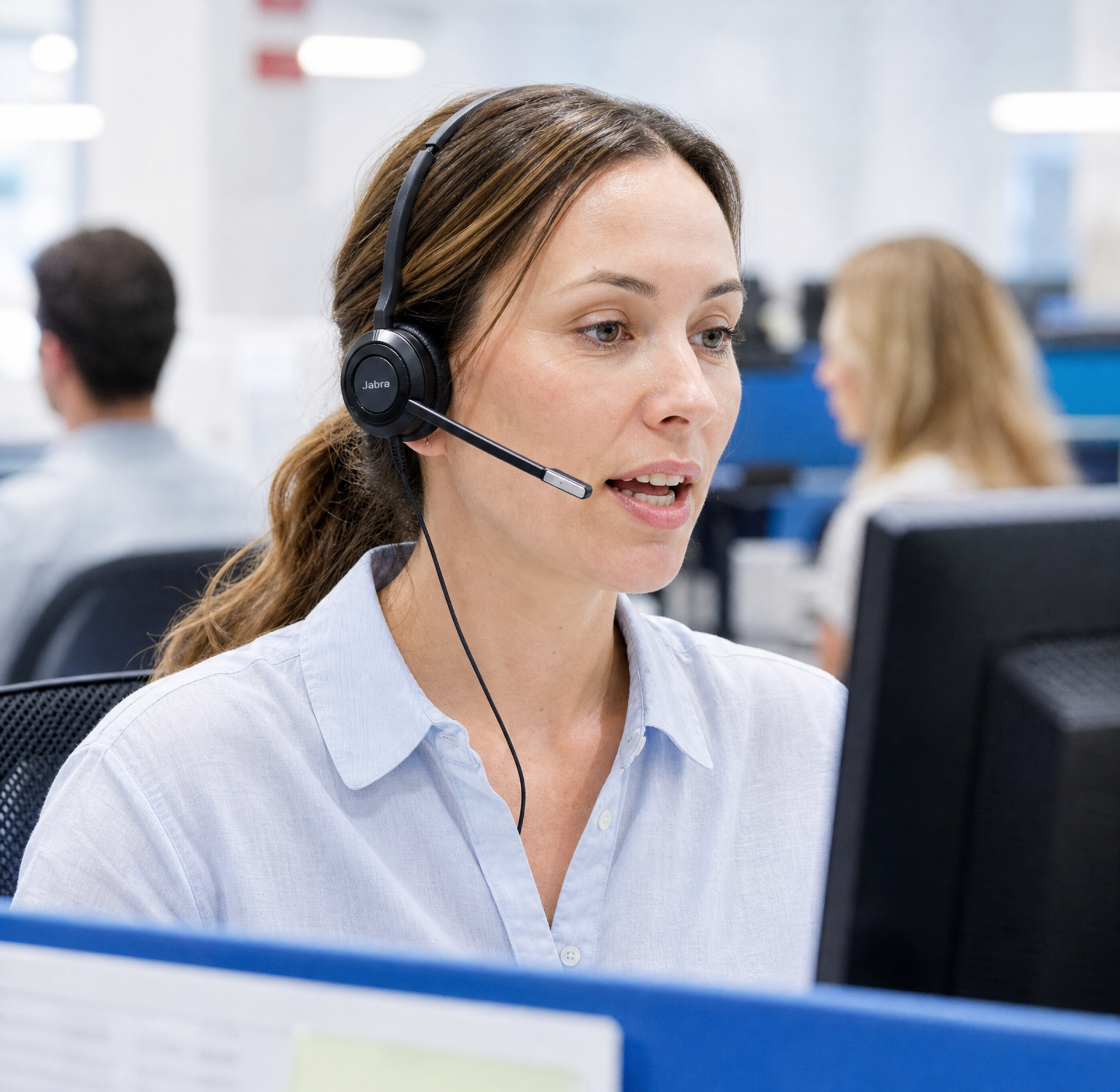 Une femme portant un casque avec micro parle à son bureau.