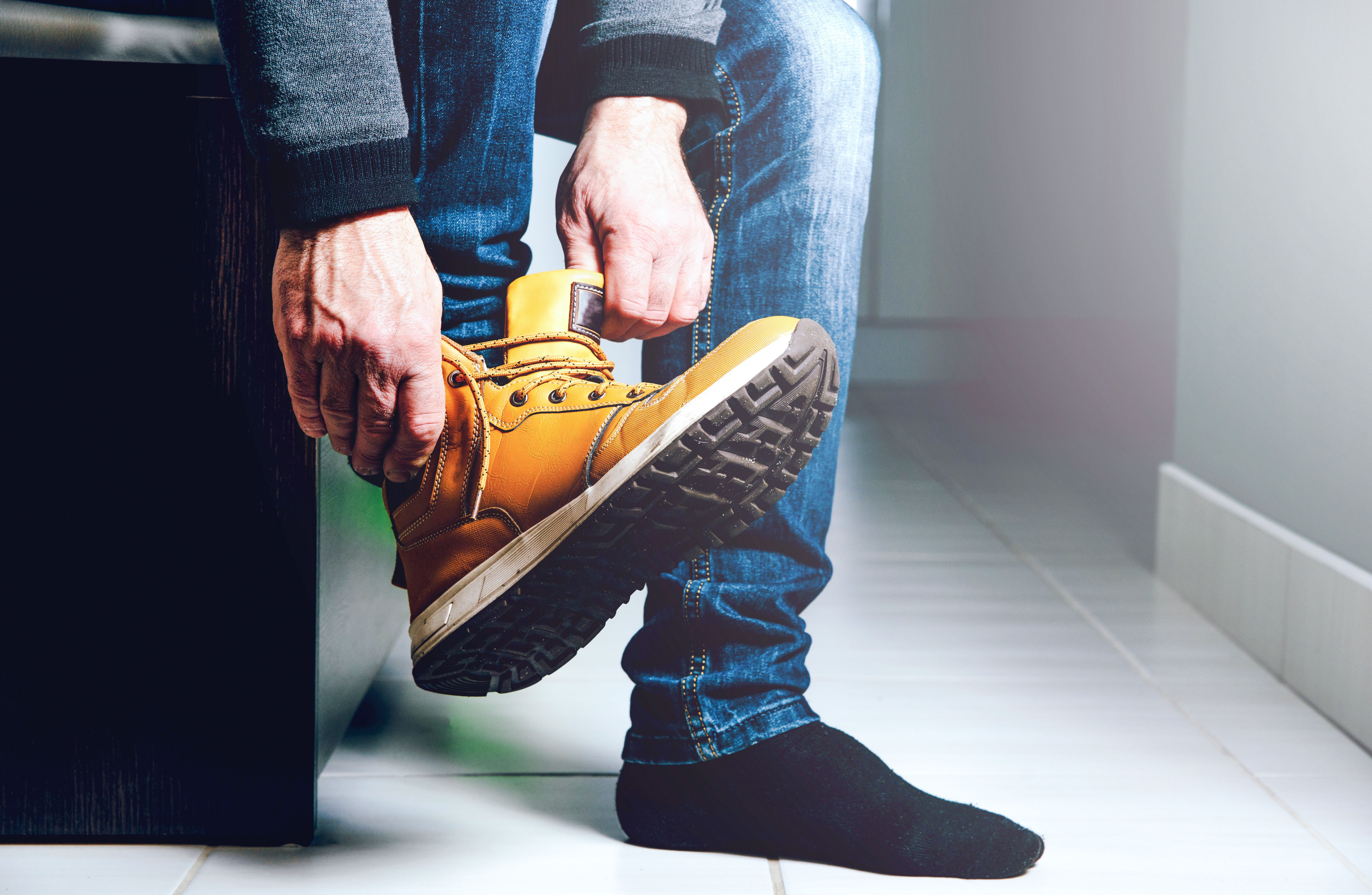Une personne enfilant une chaussure de travail beige.