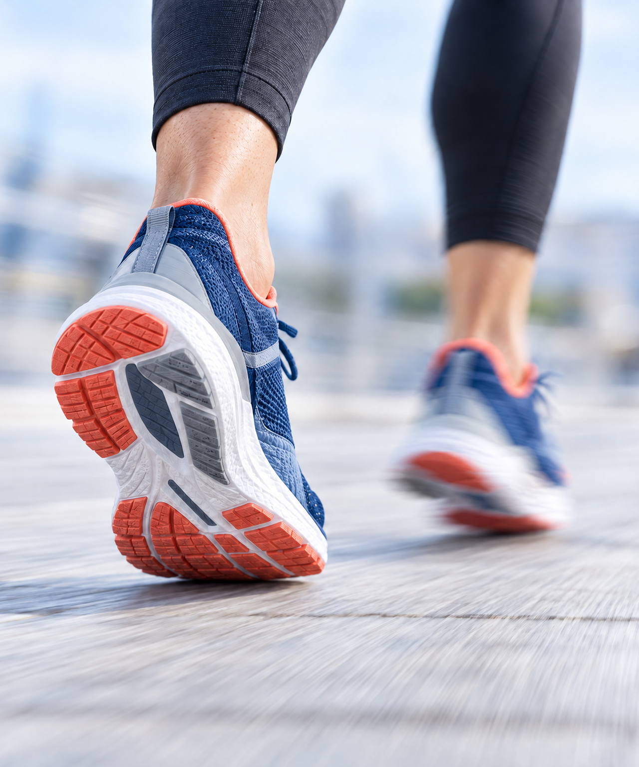 A person running in blue and orange athletic shoes, with the sole of one shoe visible.