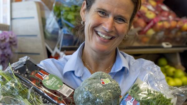 Smilende kjøpmann holder frukt og grønn som er produsert i Norge