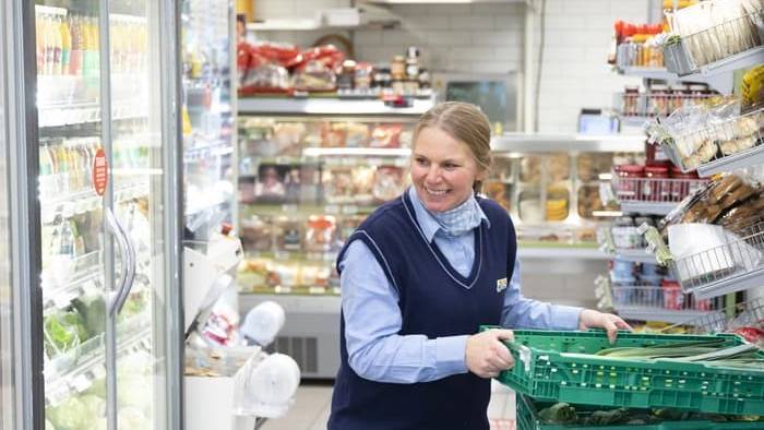 Smilende Joker-ansatt plasserer varer