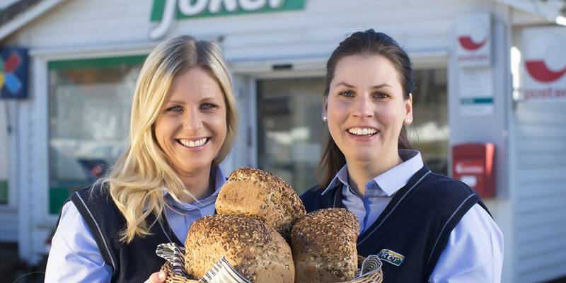 Bilde av to blide butikksjefer eller ansatte som holder opp tre ferske brød