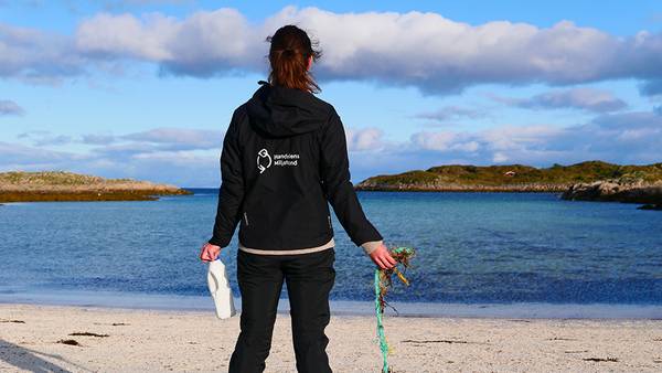 Bilde av en kvinne som plukker søppel på stranden