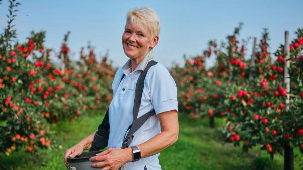 Smilende dame i en eplehage