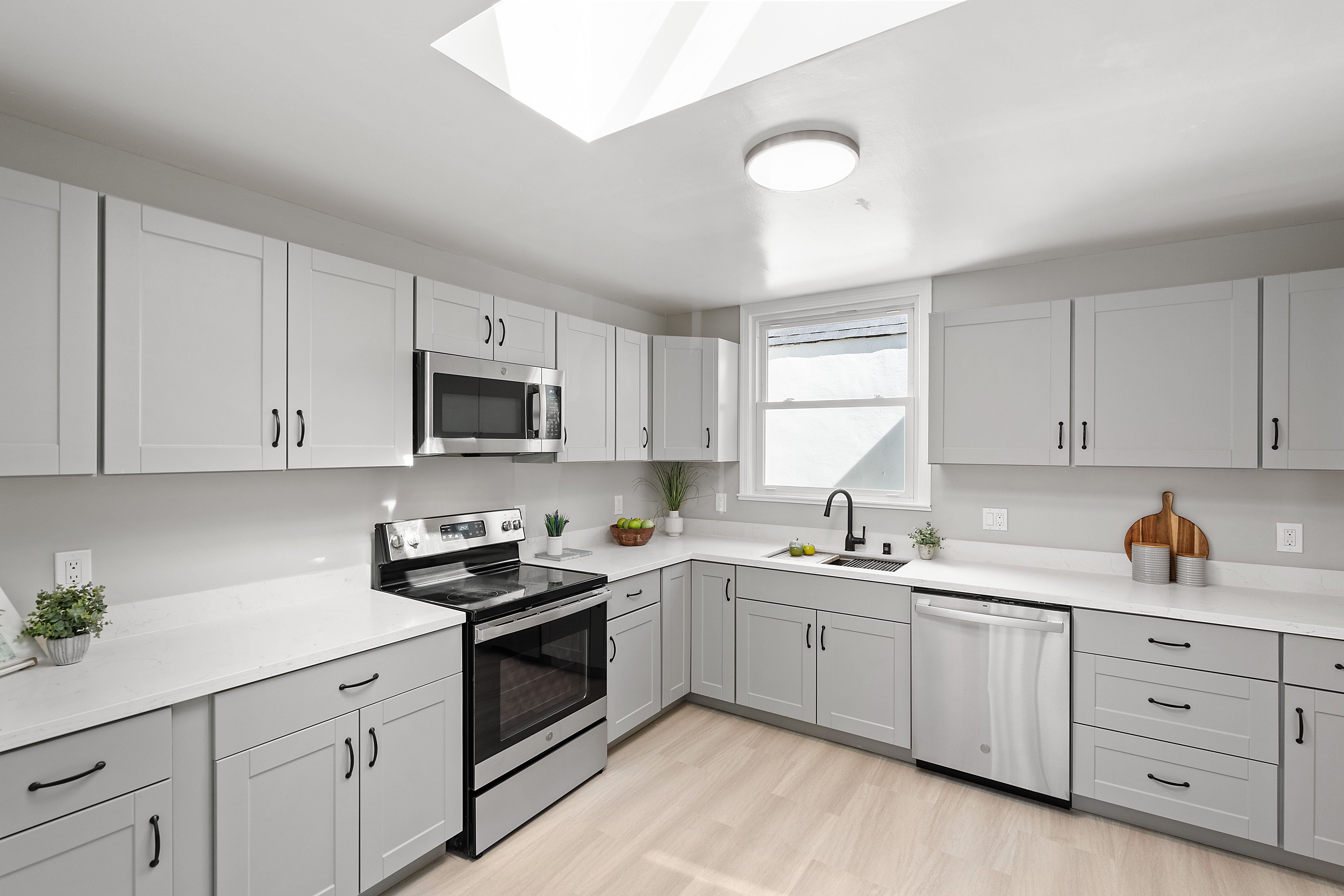 Modern kitchen with white cabinets and stainless steel appliances.