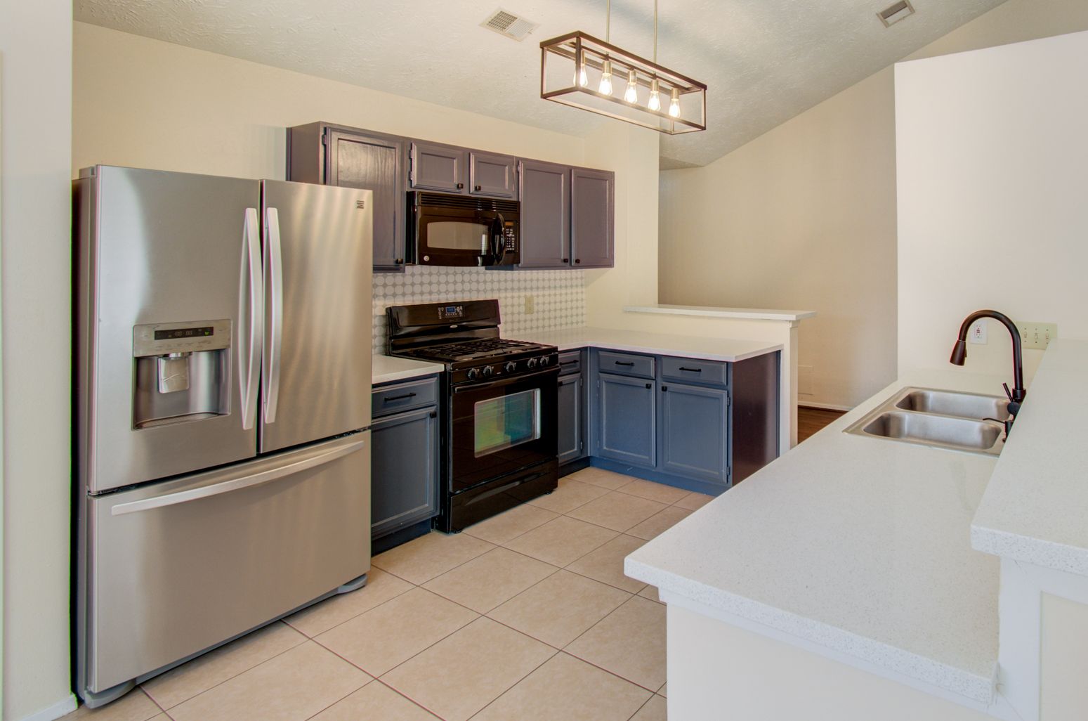 Modern kitchen with stainless steel appliances and fridge.