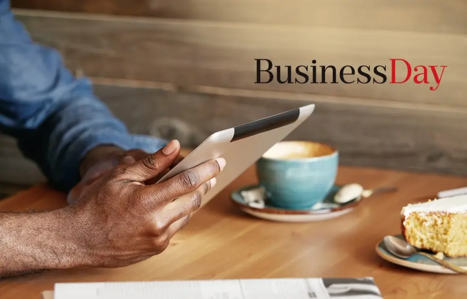 Man reading an article on his tablet with coffee and newspaper