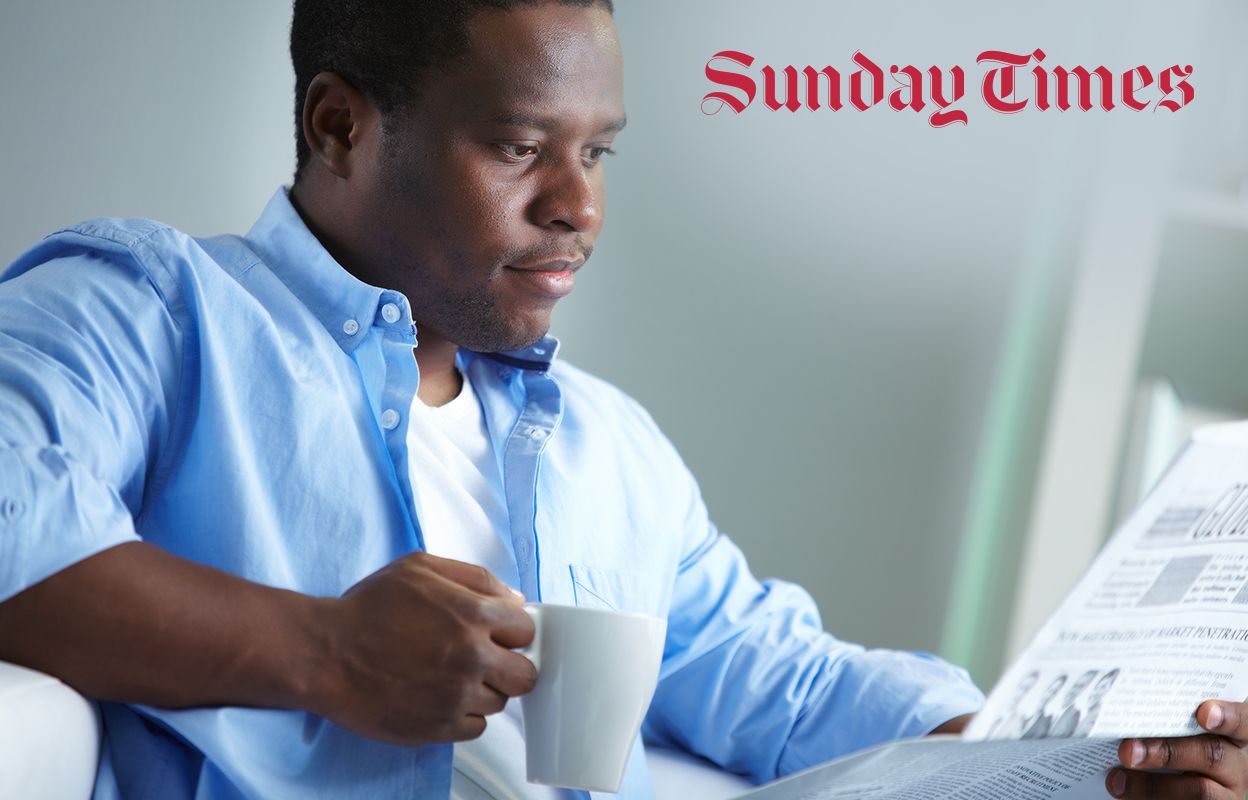 Man with coffee reading a newspaper