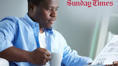 Man with coffee reading a newspaper